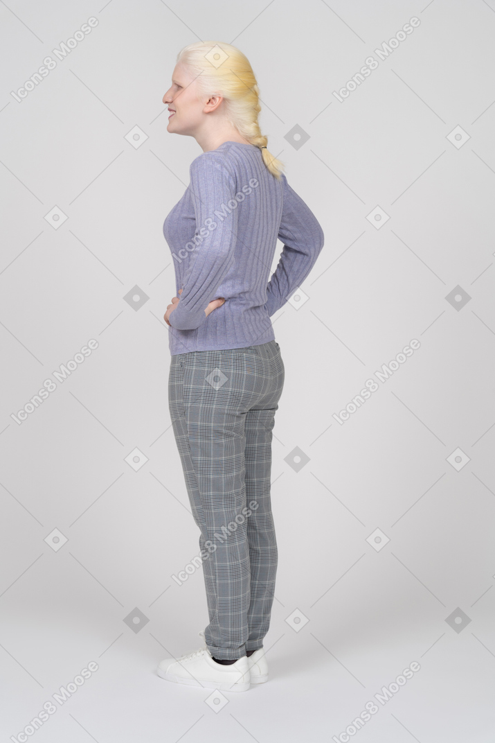 Femme gaie avec les mains sur les hanches regardant loin