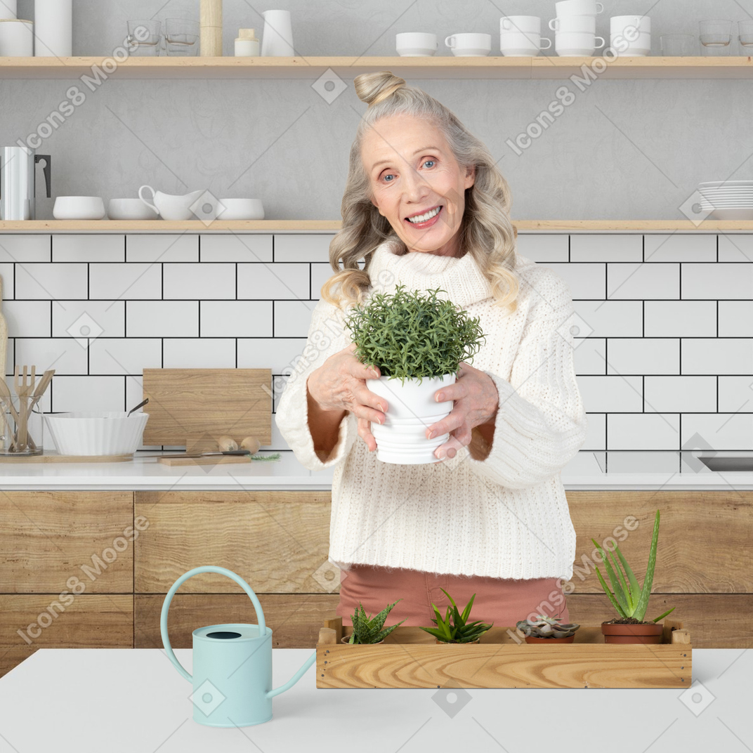 A woman holding a potted plant in a kitchen