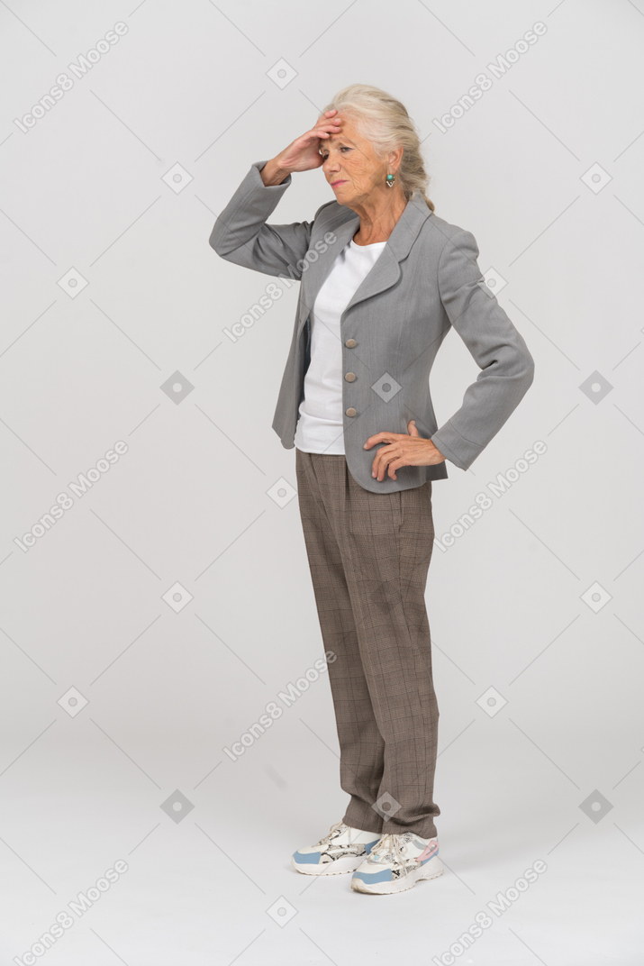 Vista lateral de uma senhora idosa de terno tocando a testa