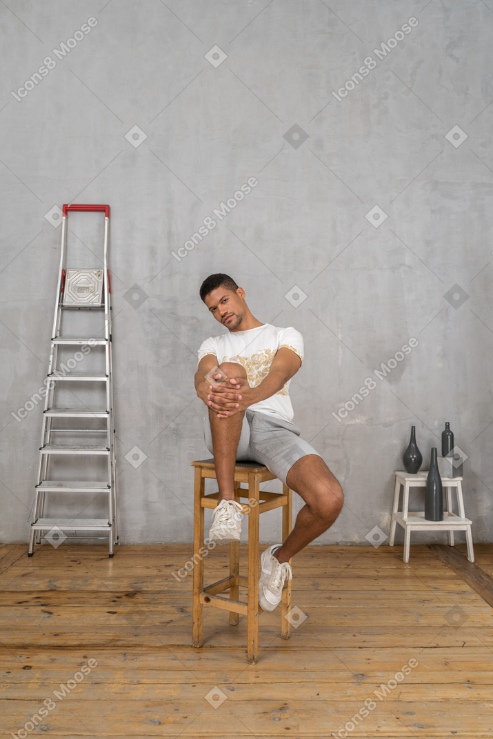 Man sitting with hands on knee and looking at camera