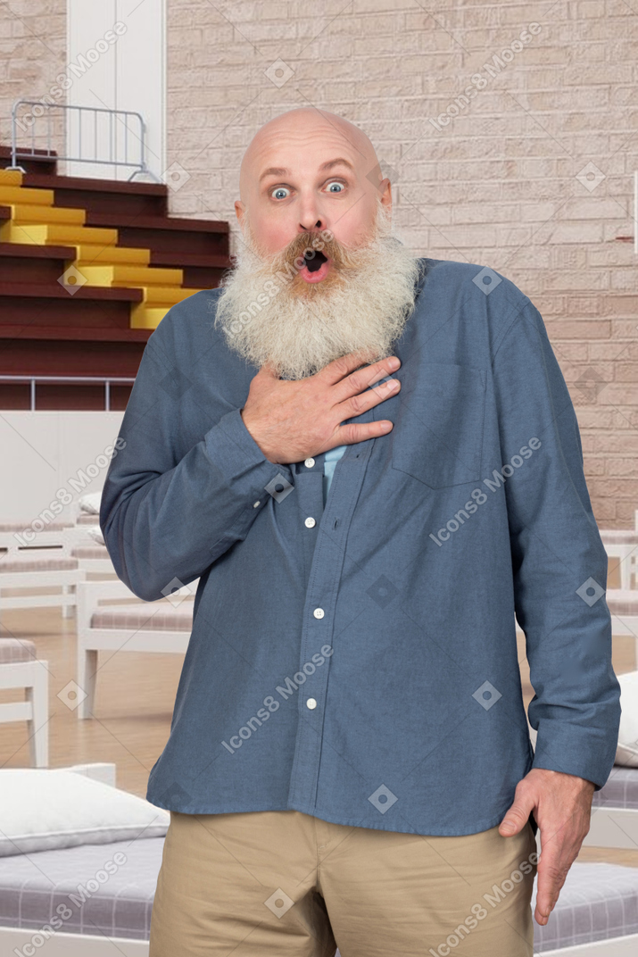 Shocked old man standing in a temporary hospital and touching his chest