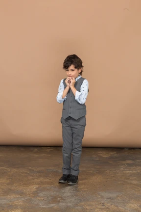Front view of a boy in grey suit making praying gesture