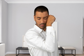 A man in a white shirt is touching his head