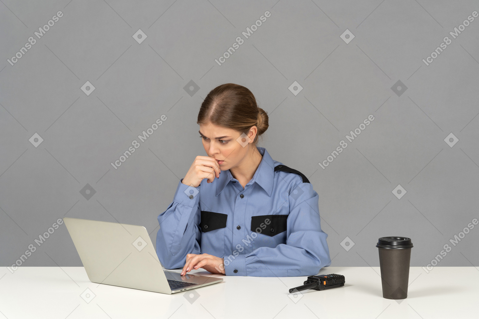 A thoughtful female security guard looking at a laptop