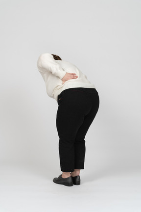 Plus size woman in casual clothes suffering from pain in lower back