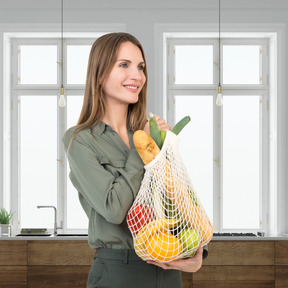 A woman holding a bag of fruit and vegetables