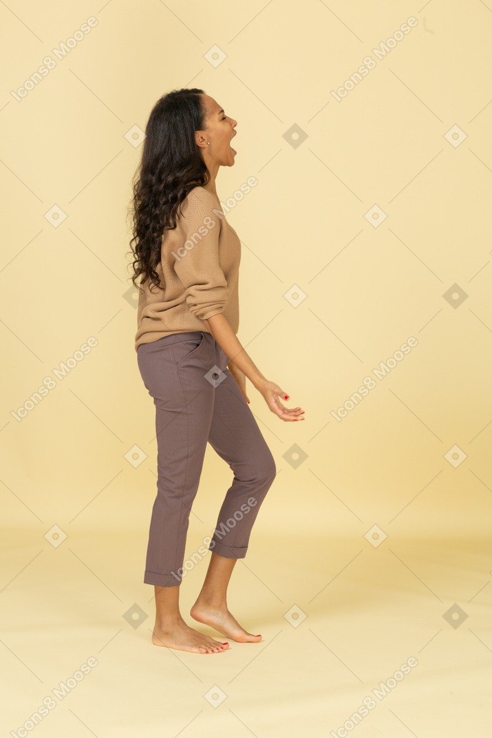 Side view of a naughty dark-skinned young female outspreading hands