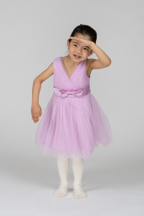 Маленькая девочка в розовом платье смотрит в сторону