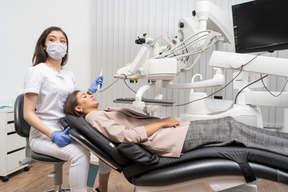 Longitud total de una dentista curando a su paciente acostada en un gabinete de hospital