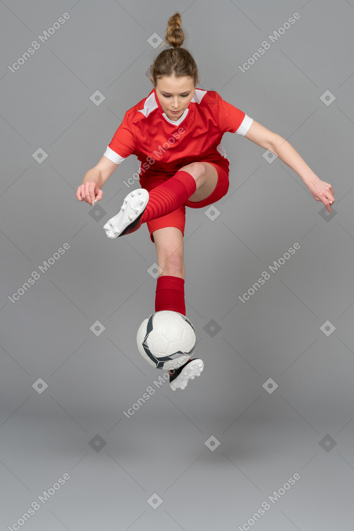 Eine sportliche junge frau, die mit ball springt