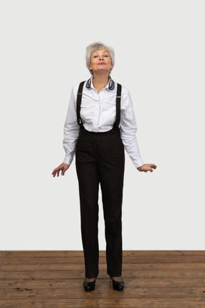 Vista frontal de una vieja mujer alegre en ropa de oficina agachándose y haciendo muecas