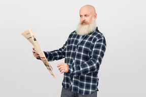 Bearded man with a newspaper looking puzzled