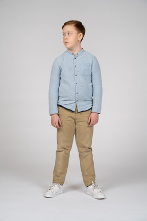 Вид спереди мальчика в повседневной одежде, смотрящего в сторону
