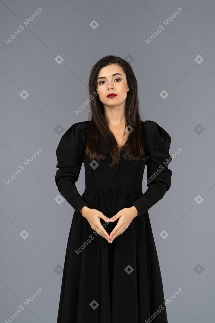 Front view of a bossy young lady in a black dress holding hands together