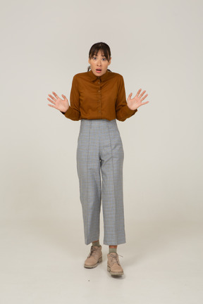 Front view of a careful young asian female in breeches and blouse outstretching her arms