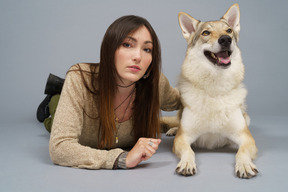 De cuerpo entero de una maestra acostada junto a su perro y mirando a la cámara