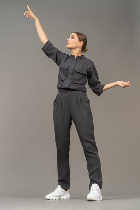 Front view of a young woman in a jumpsuit outstretching her arm