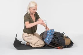 Mature female tourist organising tourist backpack