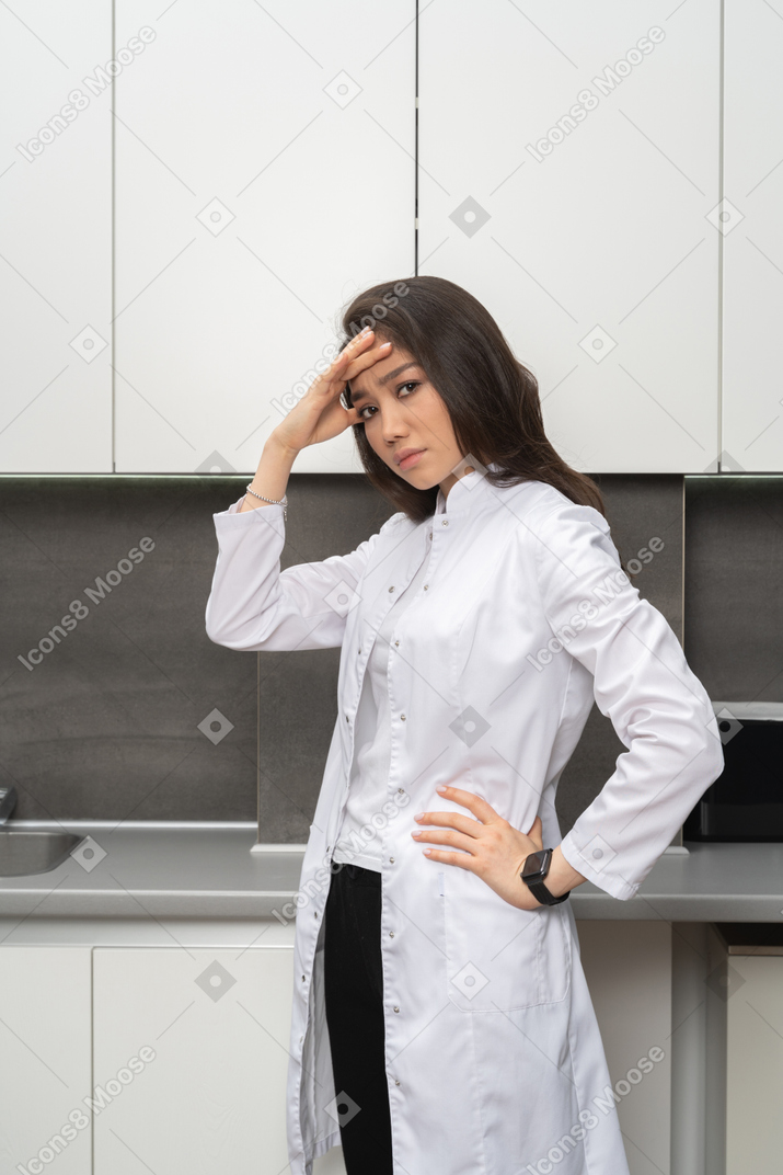 Side view of a female doctor looking at camera and hiding her face