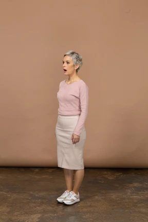Side view of a woman in casual clothes standing with her mouth open