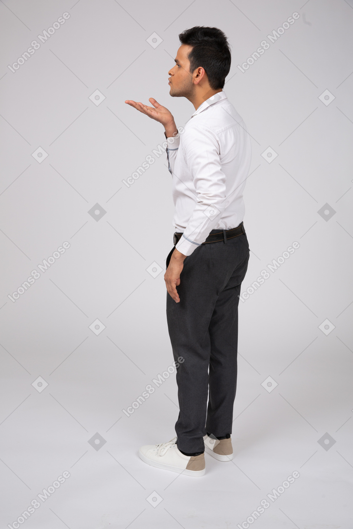 A man in a white shirt and black pants blowing a kiss