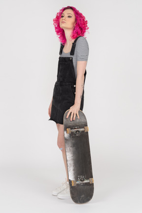 Confident teenage girl posing with a skateboard