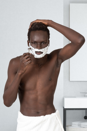 Young man shaving his beard in the bathroom