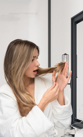 Mujer joven revisando su cabello en busca de puntas abiertas