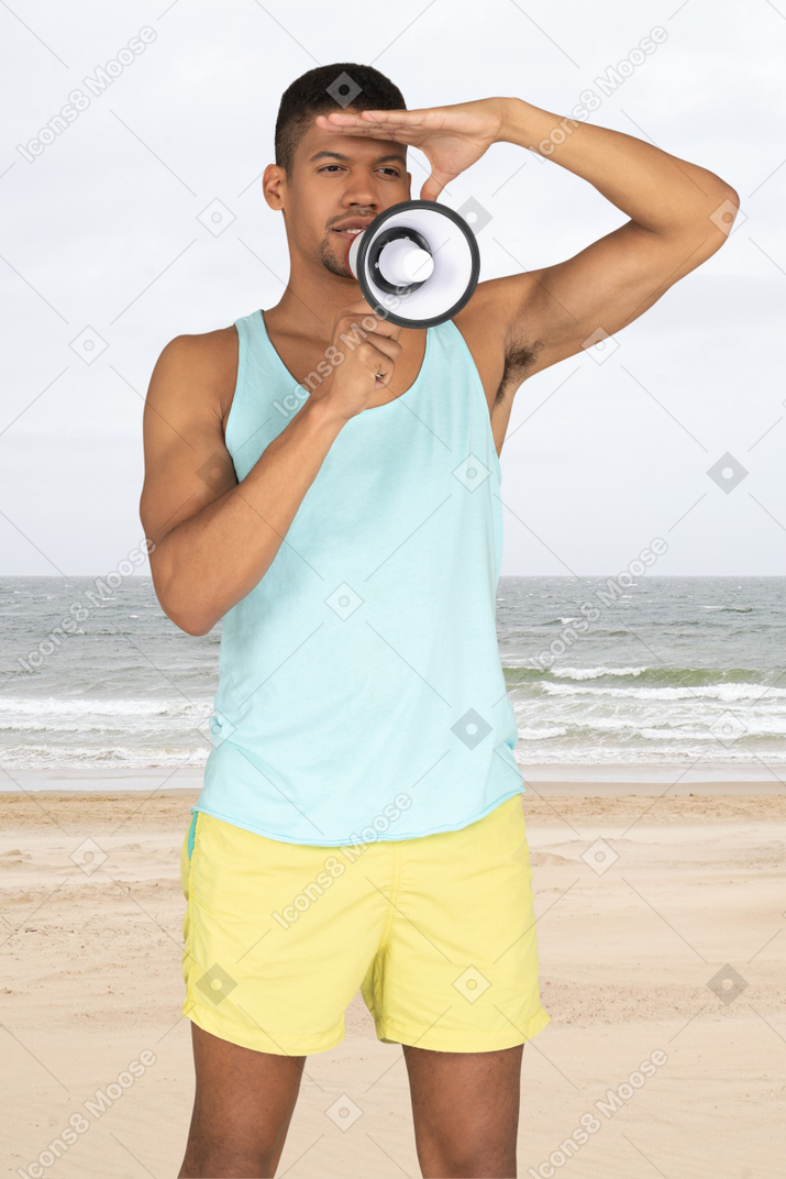A lifeguard speaking into a megaphone on the beach