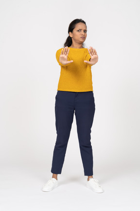Вид спереди девушки в повседневной одежде, показывающей жест стоп
