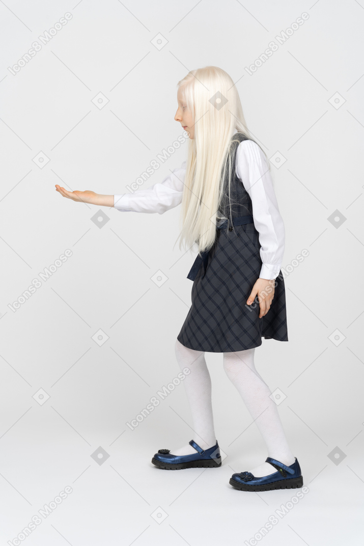 Side view of a schoolgirl holding her hand out