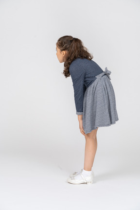 Three-quarter back view of a girl leaning forward with hands on her knees