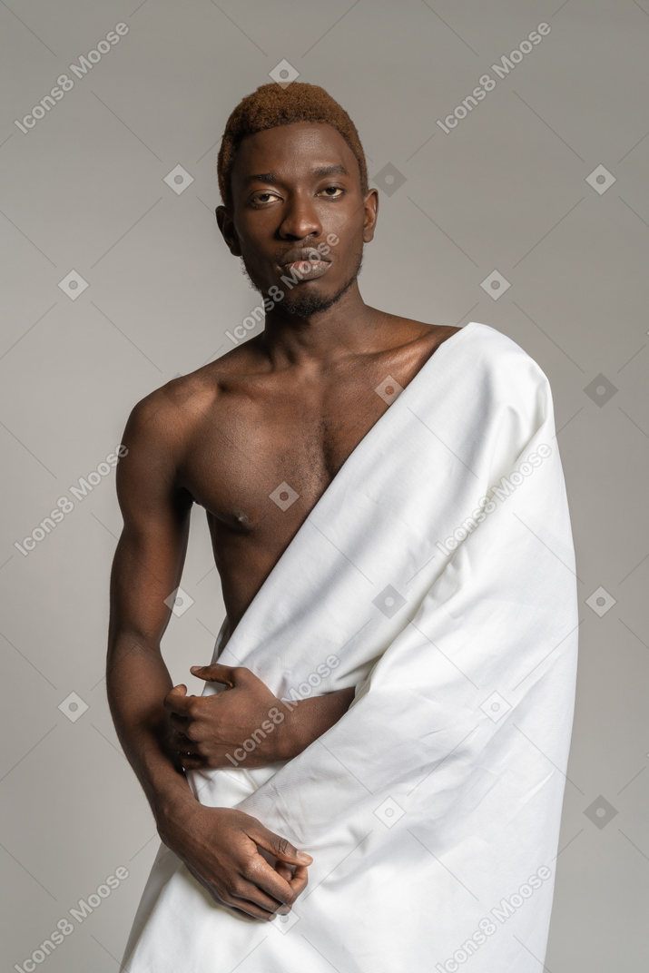 Jeune homme noir debout dans un drap blanc et regardant la caméra