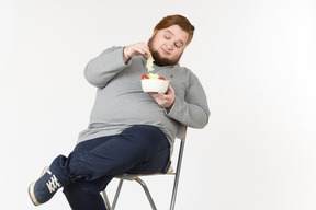 Grande ragazzo barbuto raccogliendo foglie di insalata dal piatto