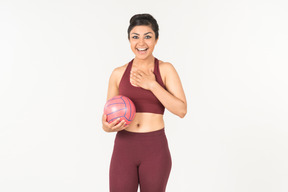 Mujer india joven sonriente que sostiene la bola rosada