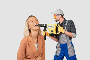 Worker using demolition hammer on woman's teeth