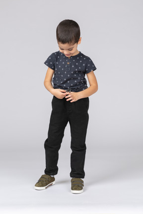 Vista frontal de um menino feliz em roupas casuais, olhando para as mãos