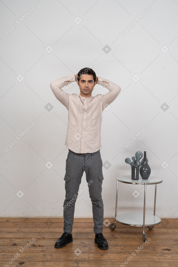 Vorderansicht eines beeindruckten mannes in freizeitkleidung, der mit den händen hinter dem kopf steht