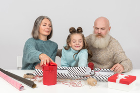 Abuelos y nieta envolviendo regalos