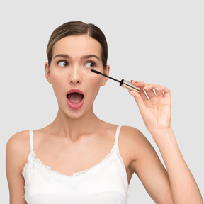 A woman applying mascara to eyelashes