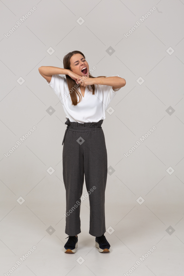 Front view of a yawning young lady in office clothing touching chin