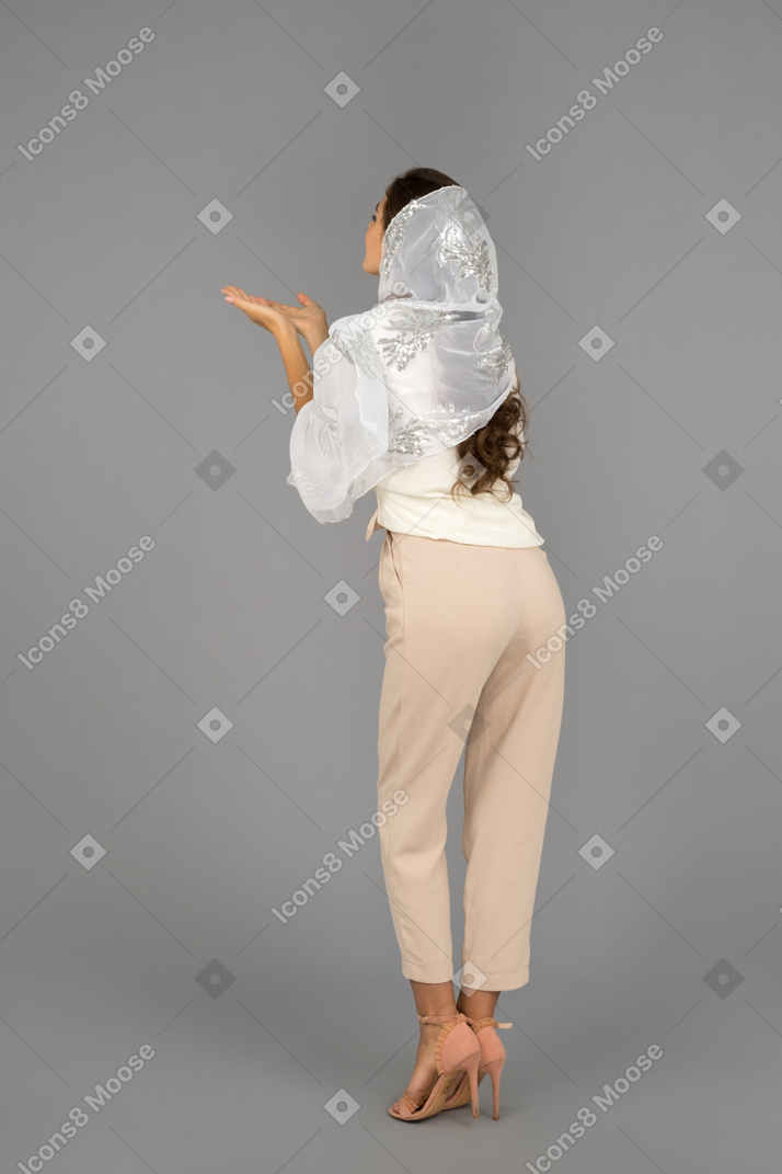 Mujer joven cubierta que sopla besos de aire a la cámara