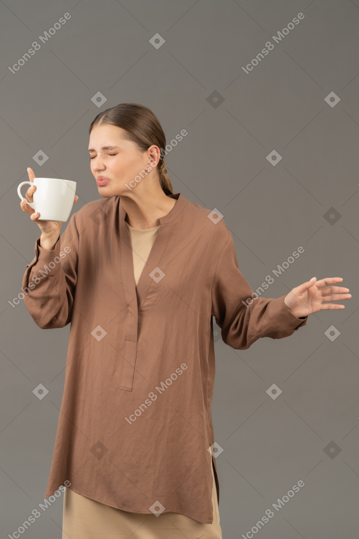 Young woman wincing while drinking coffee