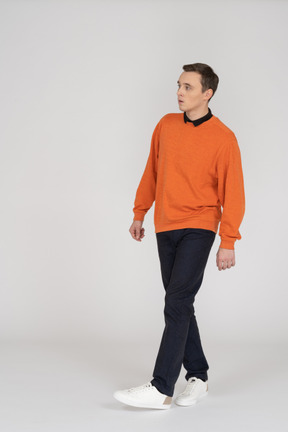 Junger mann im orangefarbenen sweatshirt zu fuß