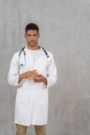 Young doctor holding a bottle of pills