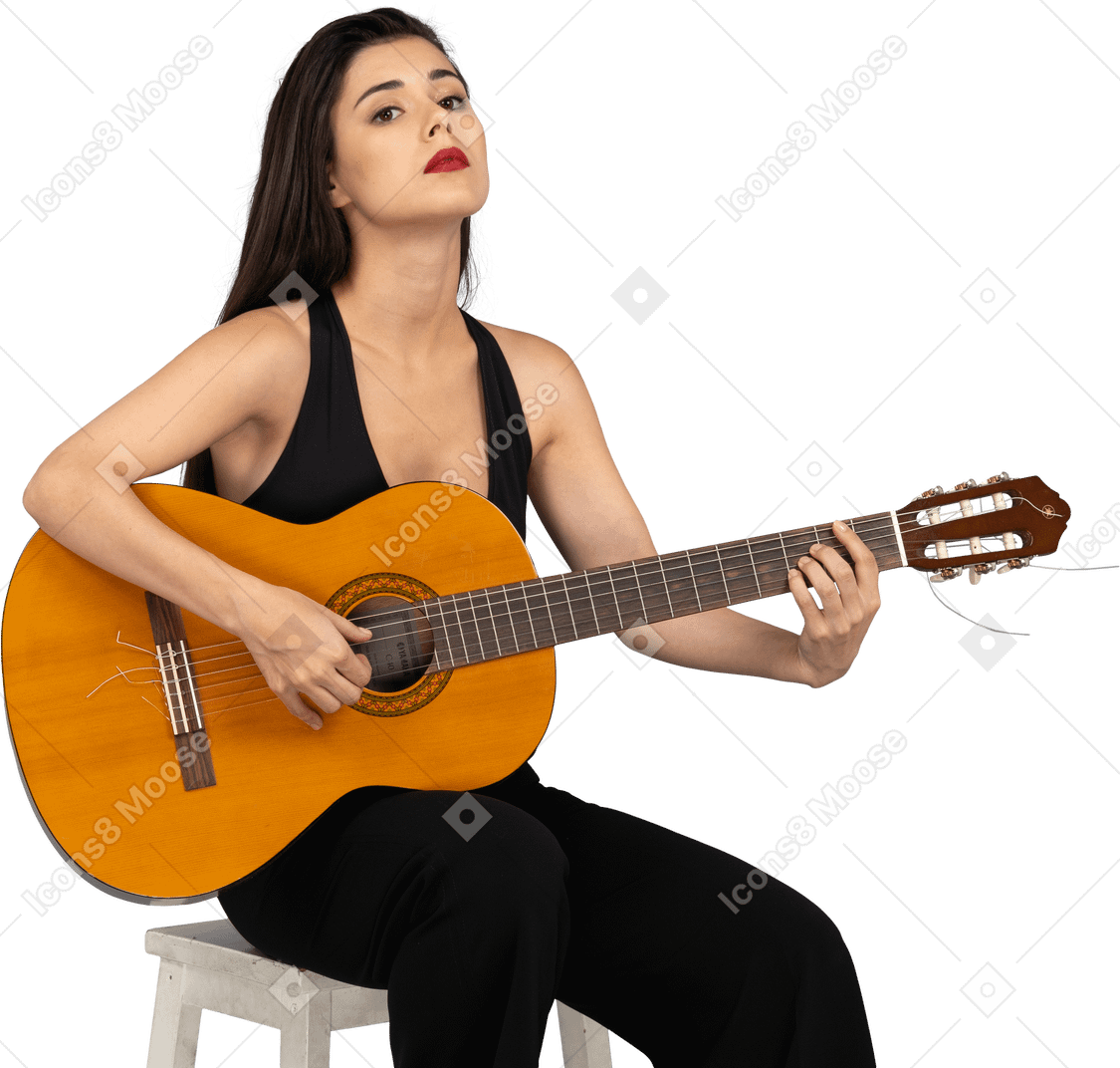 ギターを保持し、頭を上げる黒いスーツを着て座っている若い女性の正面図