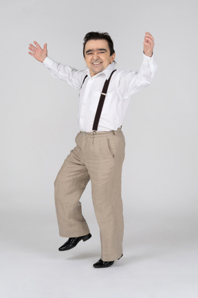 Happy middle-aged man with spread hands standing on one leg