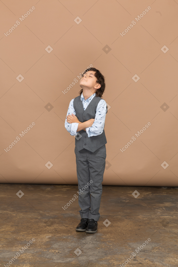 腕を組んで立っている灰色のスーツを着た少年の正面図
