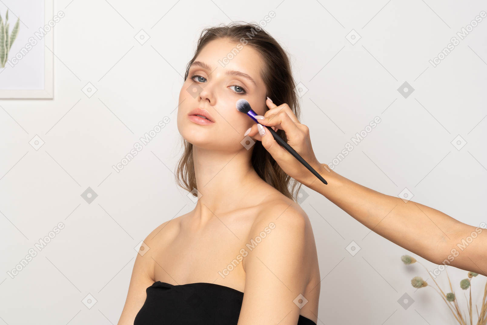 Three-quarter view of a make-up artist applying face powder for a female model