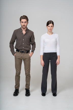 Front view of a suspicious young couple in office clothing